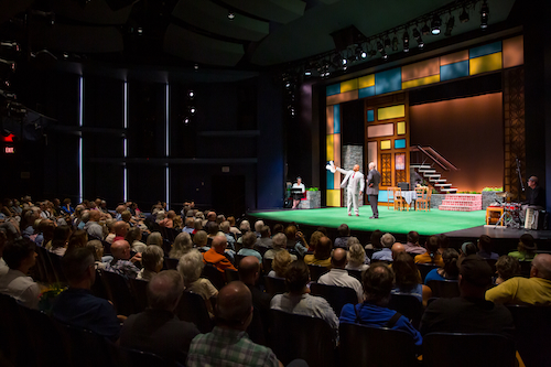 Actors on stage in smaller indoor theater with audience.