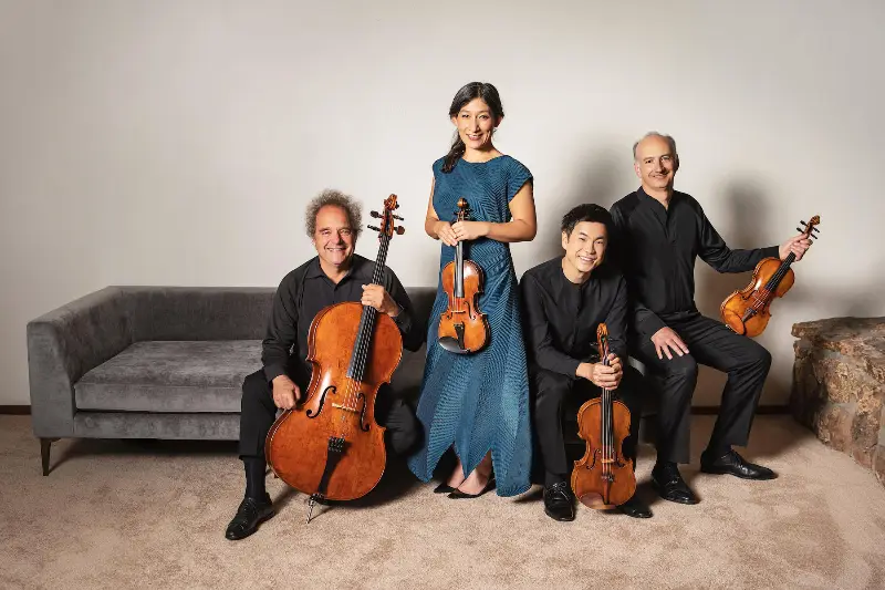 String quartet sitting on couch in white room.