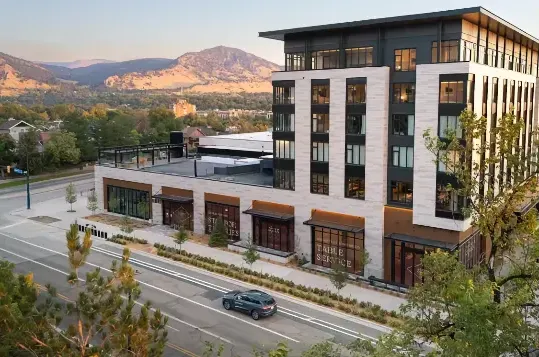Aerial photo of large modern building in front of mountains.