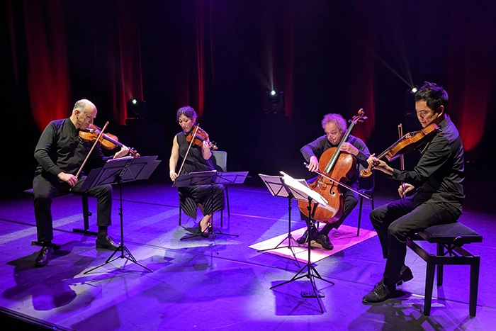 A string quartet on stage with purple light